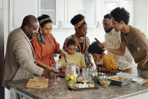 A black family in their kitchen gather to eat and talk.